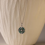 Malachite Compass Locket Necklace featuring a green and silver pendant, displayed on a textured beige background.