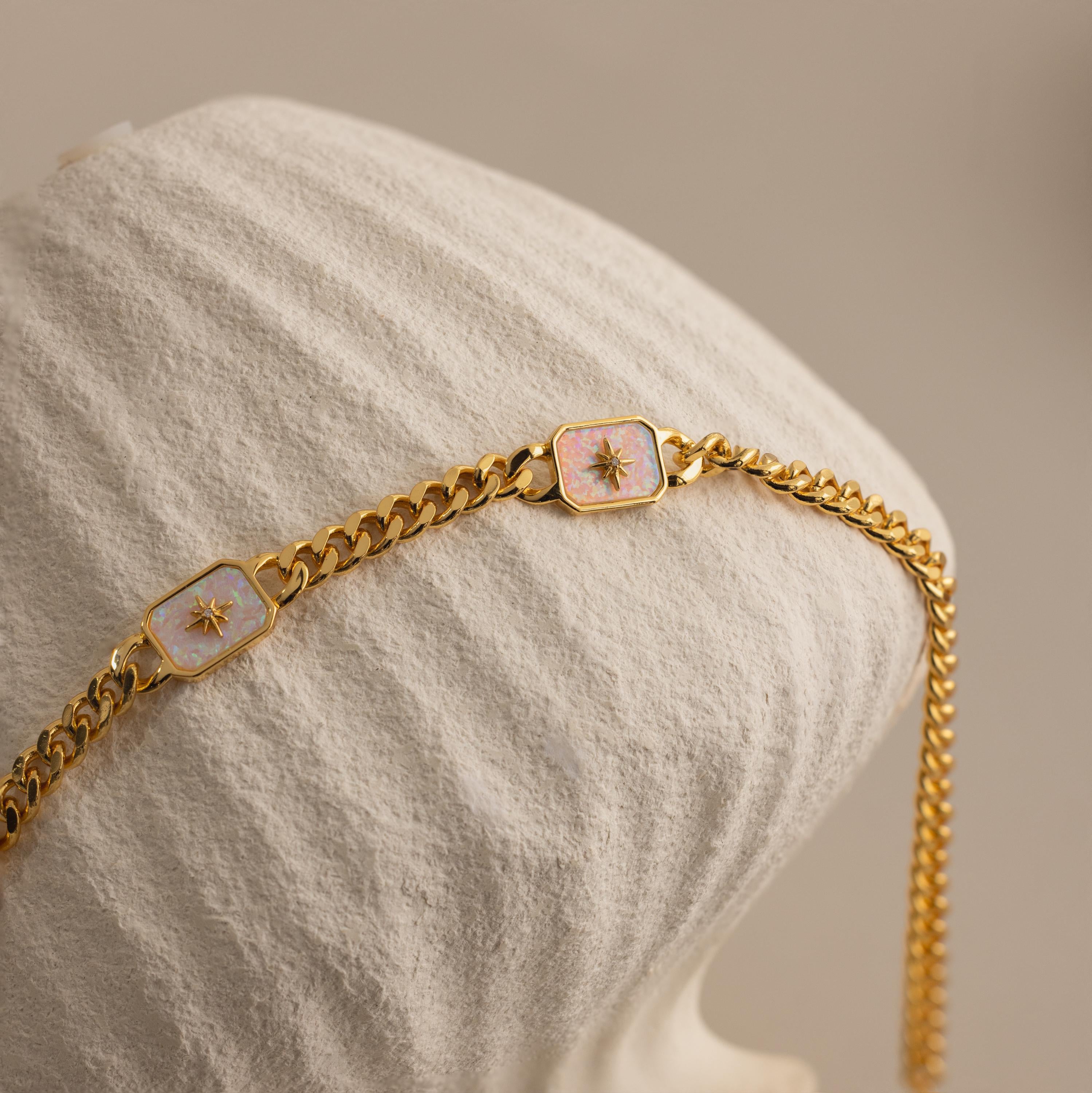 Close-up of Gold North Star Opal Necklace draped over a textured cream vase.