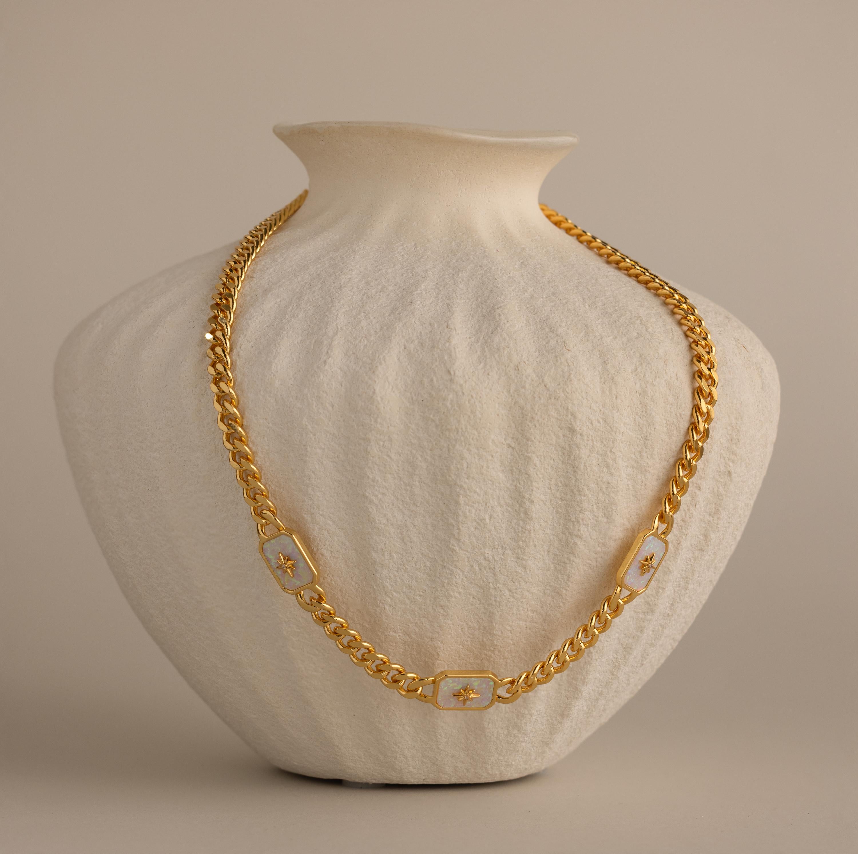 Gold North Star Opal Necklace displayed on a textured cream vase.