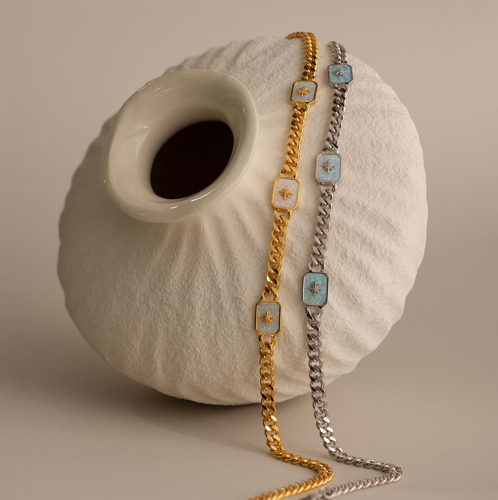 Gold & Silver North Star Opal Necklaces draped over a cream vase.