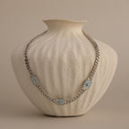 Silver North Star Opal Necklace displayed on a textured cream vase.