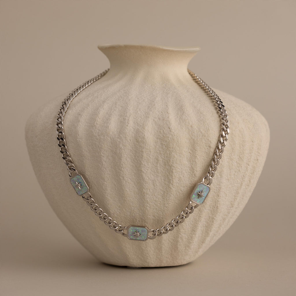 Silver North Star Trio Opal Curb Chain Necklace displayed on a textured cream vase.