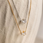Two Pearl Diamond Necklaces with pearl and teardrop diamond pendants on gold and silver chains, displayed on a textured surface.