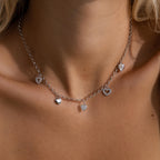 Model wearing a silver heart charm necklace featuring five unique heart pendants.