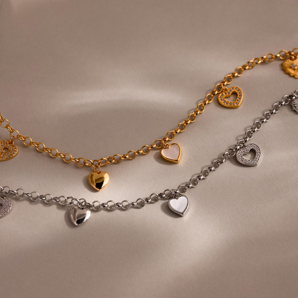 Gold and silver heart charm necklaces with five assorted heart pendants in glossy, enamel, and crystal finishes, displayed side by side.