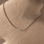 The Love Knot Chain Necklace in White Gold is displayed on a textured beige mannequin bust, symbolizing meaningful bonds.