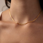 A close-up of a woman’s neck adorned with the Love Knot Chain Necklace in 18K Gold, featuring a delicate knot at the center that symbolizes meaningful bonds.