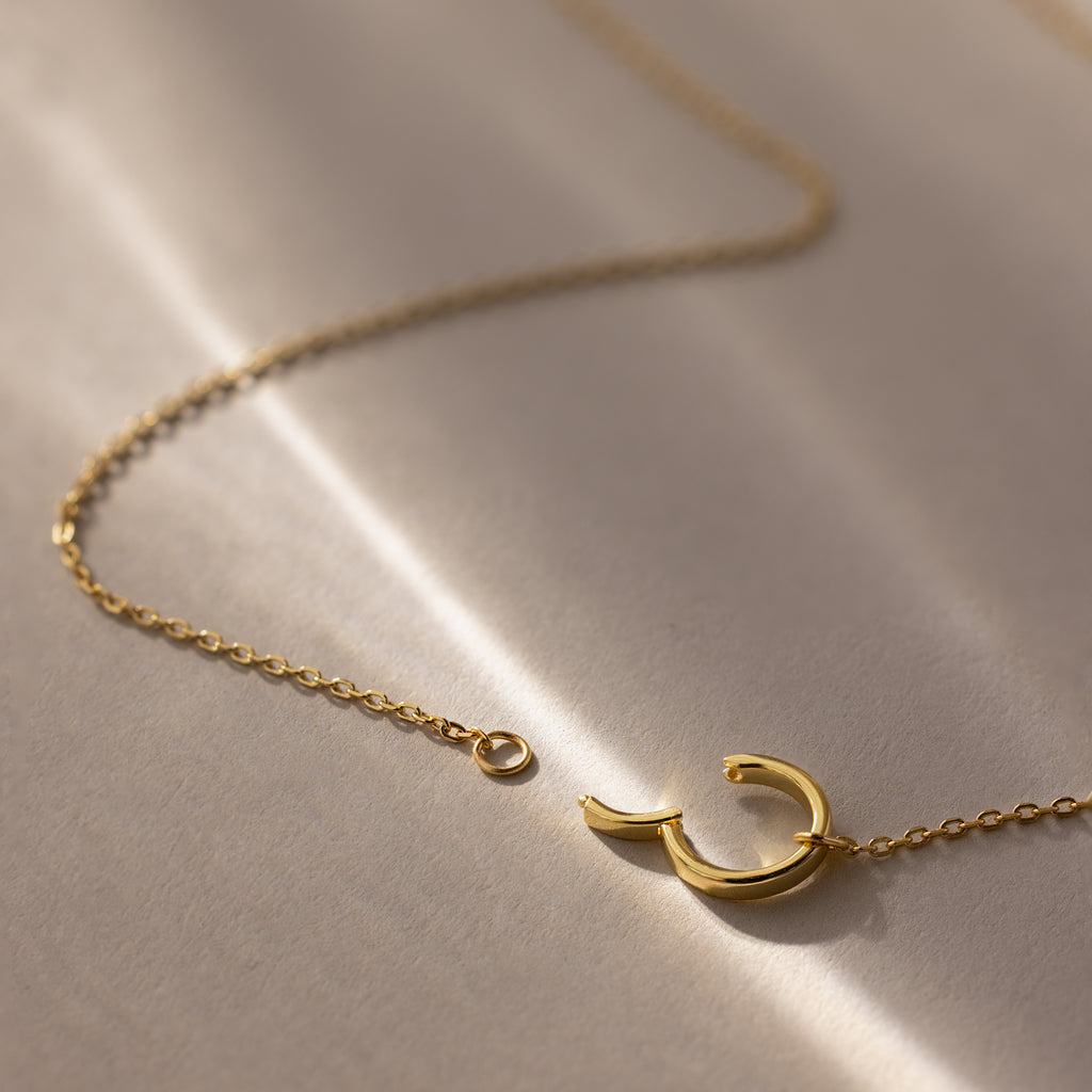 The Large Rolo Clasp Necklace in 18K Gold features a crescent moon pendant and rests elegantly on a soft beige surface, making it ideal as a statement piece or for layering in your jewelry collection.