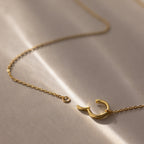 The Large Rolo Clasp Necklace in 18K Gold features a crescent moon pendant and rests elegantly on a soft beige surface, making it ideal as a statement piece or for layering in your jewelry collection.