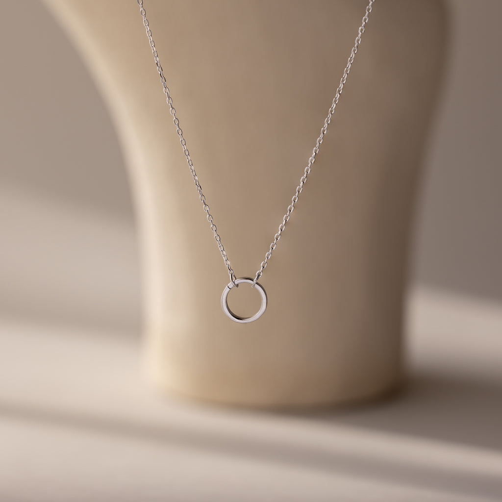 The Large Rolo Clasp Necklace in Sterling Silver features a simple circular pendant and a bold rolo clasp, making it a versatile accessory. Displayed on a neutral background, this delicate piece is perfect for everyday wear.