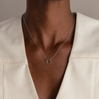 A person wearing the Large Rolo Clasp Necklace in Sterling Silver, a versatile staple, paired with a cream-colored V-neck top.
