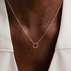 Close-up of the Large Rolo Clasp Necklace in 18K Gold, featuring a simple circle pendant, styled for layering and paired with a white blazer.
