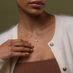 Close-up of a model wearing our Diamond Poinsettia Necklace, dressed in a beige cardigan and brown top.