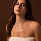 A woman with long brown hair wears a strapless white top and a Diamond Pearl Droplet Necklace in Sterling Silver against a brown background.