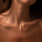 A woman wears the elegant Pearl Cascade Necklace in Sterling Silver, its three luminous pearls delicately resting against her bare skin.