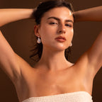 Woman with dark hair poses with arms raised, wearing a strapless off-white top and Diamond Baroque Pearl Studs in Sterling Silver.