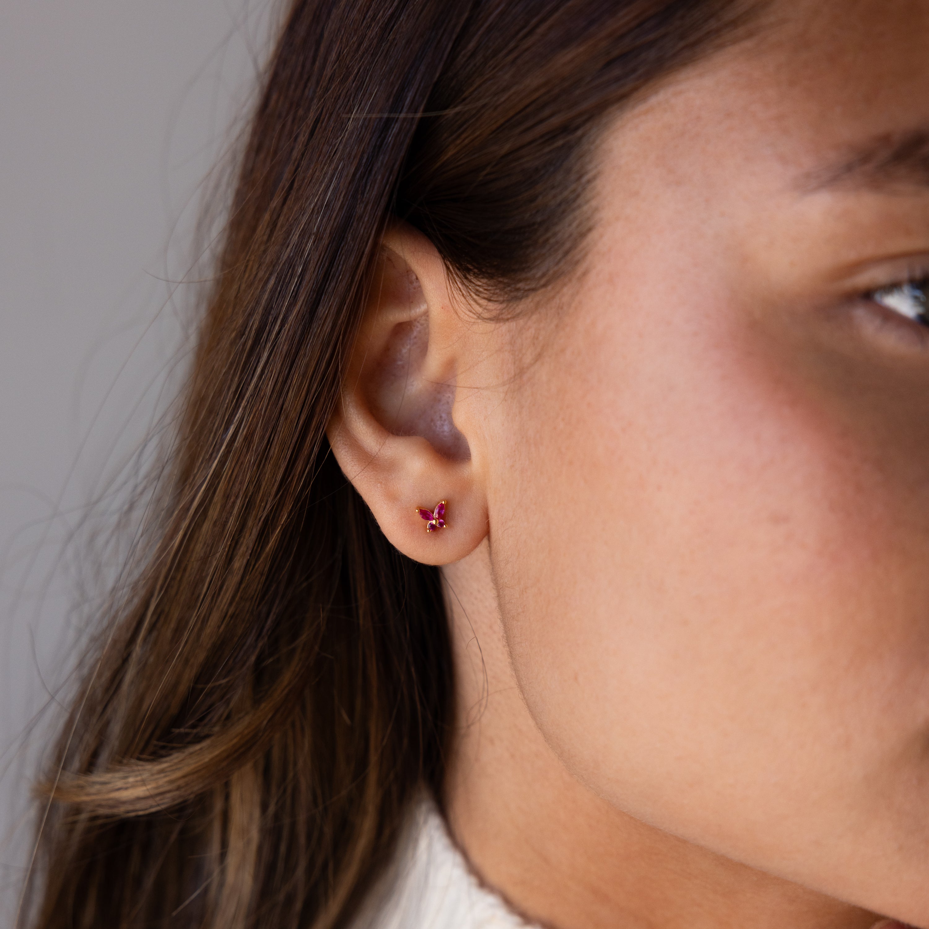 Close-up of a womans ear wearing Butterfly Garnet Flatback Studs—a small, elegant earring perfect for lovers of personalized jewelry.