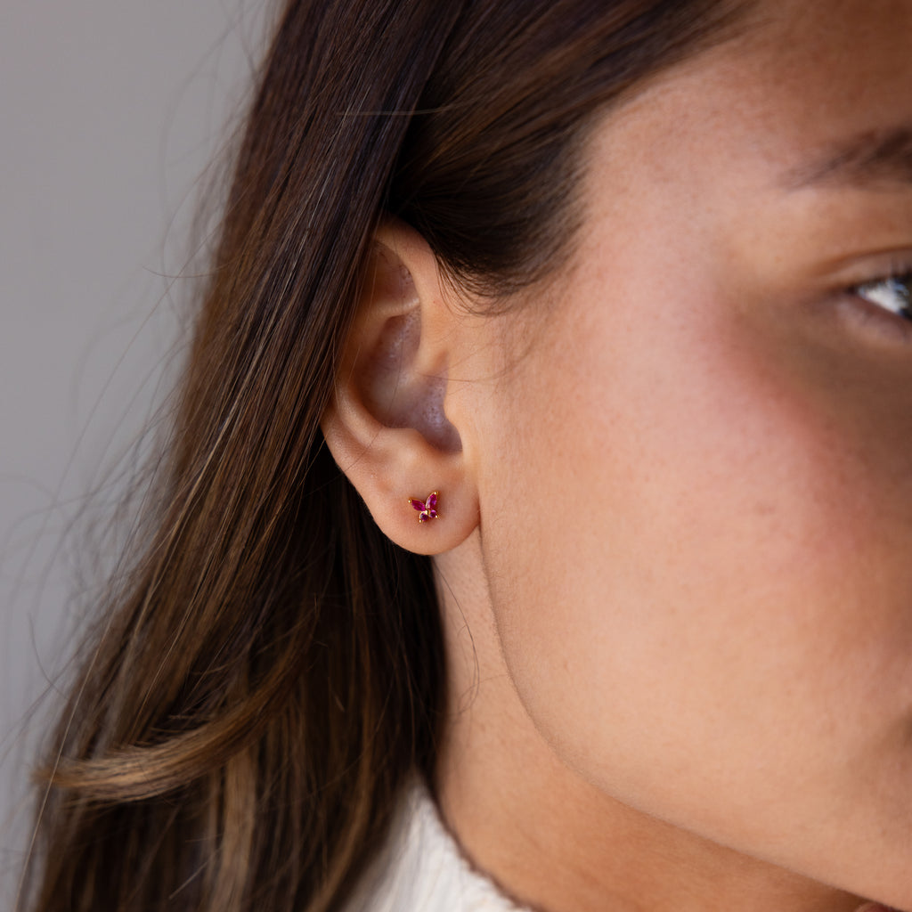 Close-up of a womans ear wearing a small Butterfly Amethyst Flatback Stud earring.