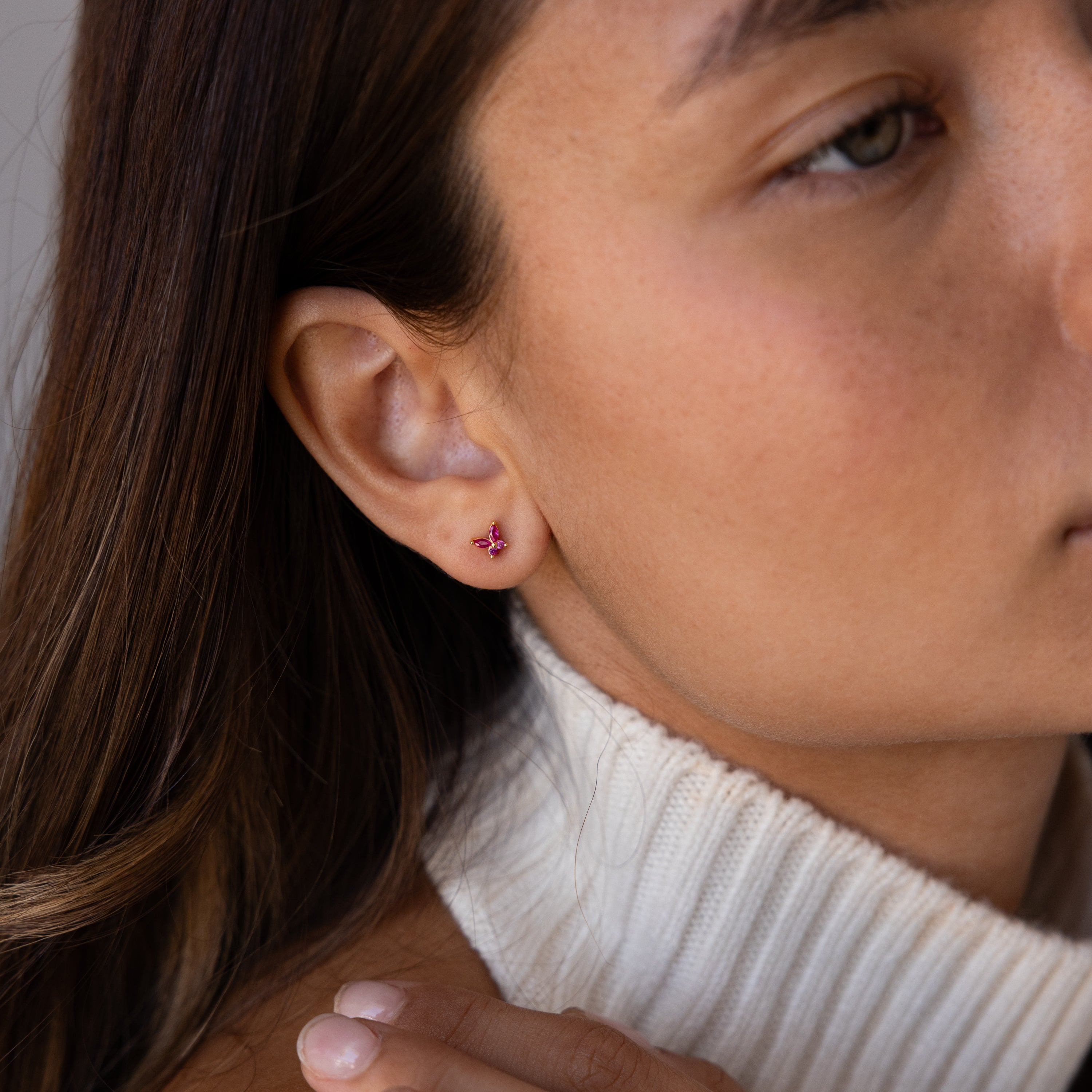 Close-up of a woman wearing Butterfly Amethyst Flatback Studs with a white turtleneck sweater.