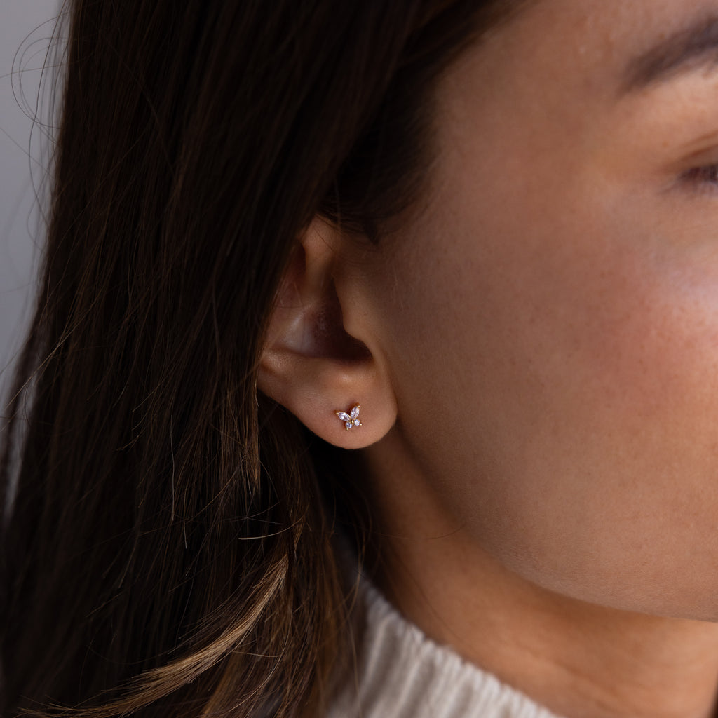 Close-up of a womans ear wearing Butterfly Blue Zircon Flatback Studs, delicate butterfly earrings with small gemstones—perfect for fans of birthstone studs.