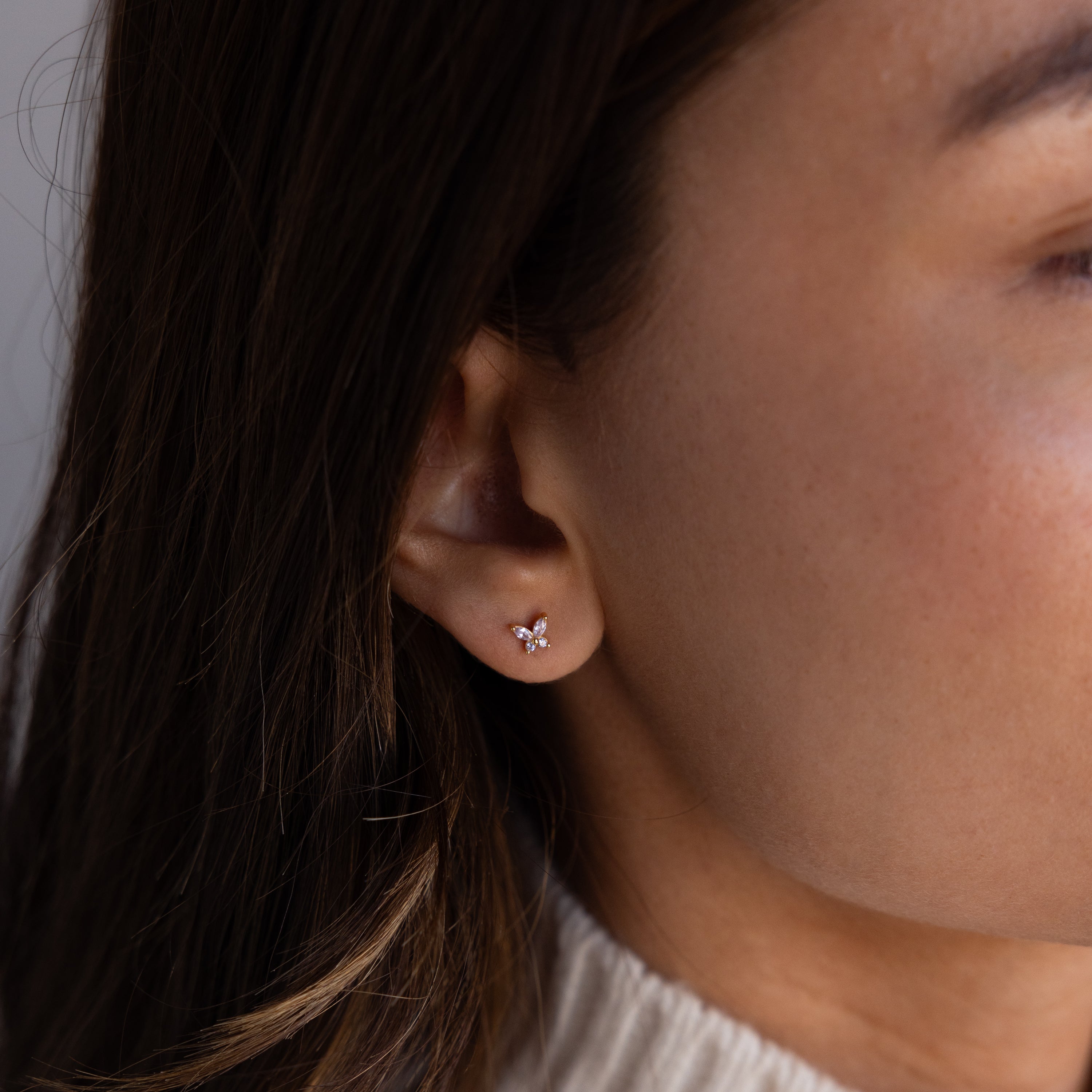 Close-up of a womans ear wearing Butterfly Blue Zircon Flatback Studs, delicate butterfly earrings with small gemstones—perfect for fans of birthstone studs.