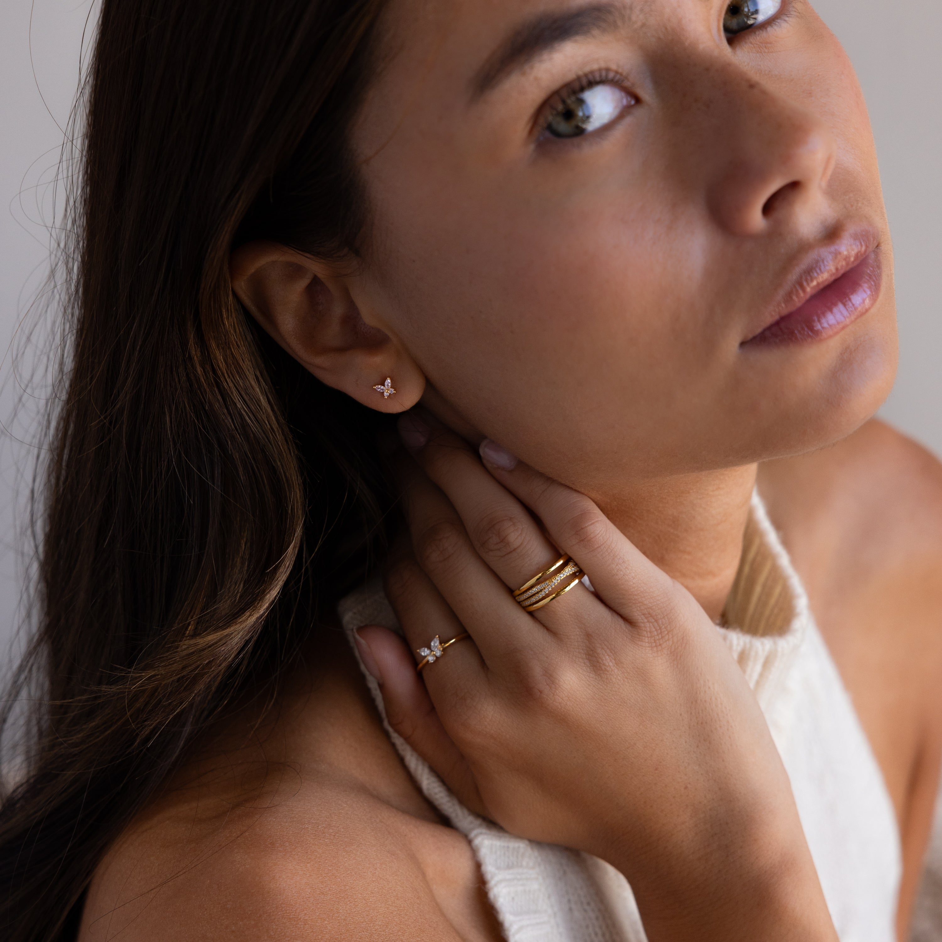 Woman with long brown hair in a cream top and gold rings wears Butterfly Amethyst Flatback Studs, gazing upwards.