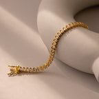 The S-Link Diamond Tennis Bracelet, adorned with shimmering stones, drapes elegantly over a curved beige ceramic object set against a neutral background.