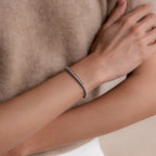 A person wearing the S-Link Diamond Tennis Bracelet in White Gold on their wrist, arms crossed over a beige sweater.