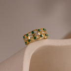 Gold checkered band ring featuring alternating rows of emerald and diamond round-cut CZ stones set in an openwork grid design.