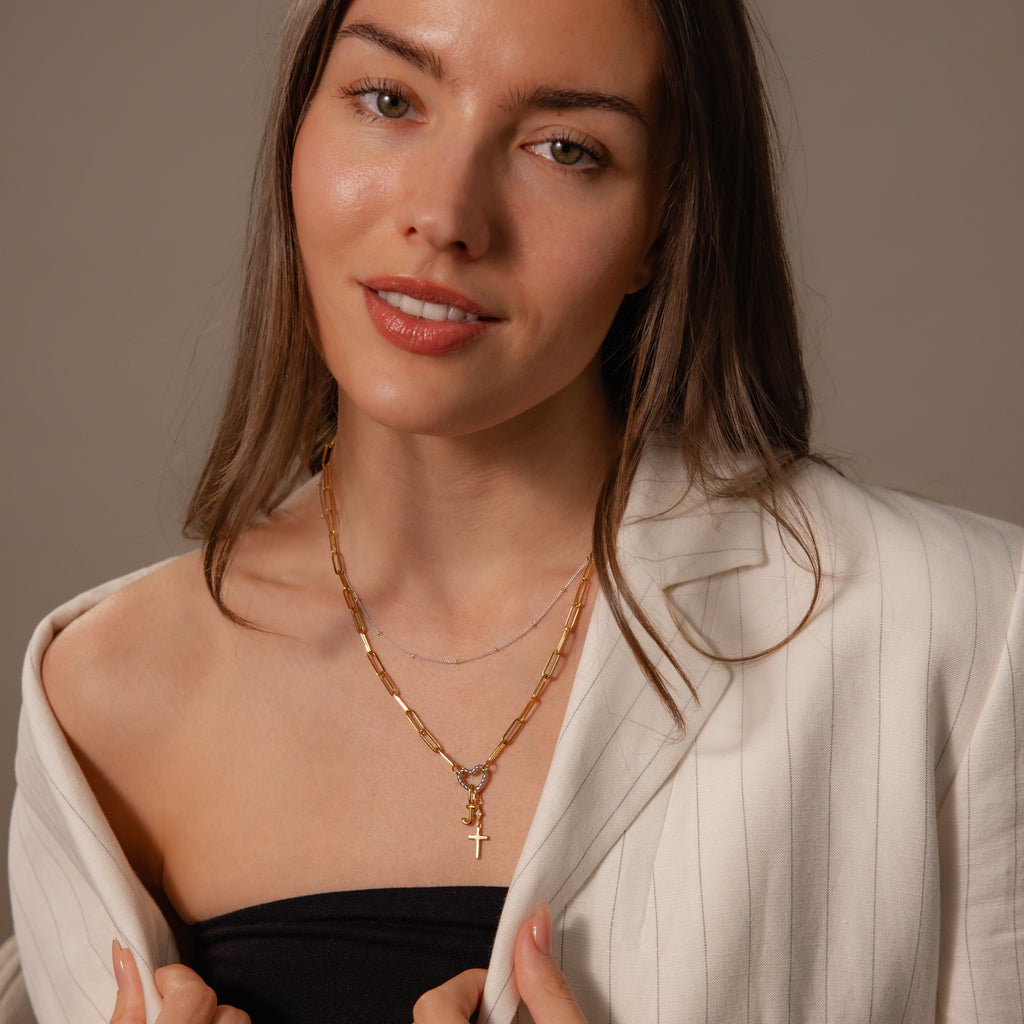 A woman in a white pinstripe blazer and black top smiles at the camera, wearing a layering necklace featuring the Mixed Metal Beaded Necklace.