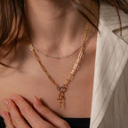 A woman wearing the Mixed Metal Beaded Necklace and a pinstripe blazer, with her hand resting on her chest.