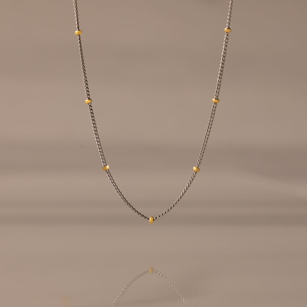 The Mixed Metal Beaded Necklace features a silver satellite chain with small gold beads evenly spaced—ideal for layering.