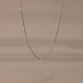 The Mixed Metal Beaded Necklace features a silver satellite chain with small gold beads evenly spaced—ideal for layering.