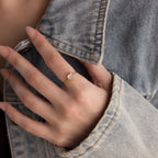 A hand adorned with the Moonstone Heart Ring shines atop a denim jacket sleeve.