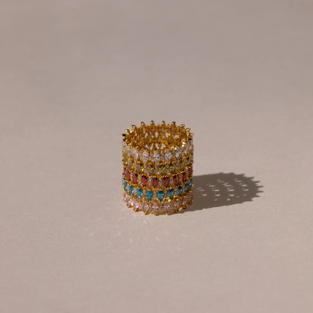 The Marquise Infinity Birthstone Ring, with vibrant gemstones arranged in multiple rows, rests on a neutral background and casts a gentle shadow.