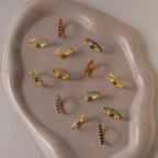 The Marquise Infinity Birthstone Ring, featuring colorful gemstones, is displayed on an irregularly shaped beige ceramic tray.