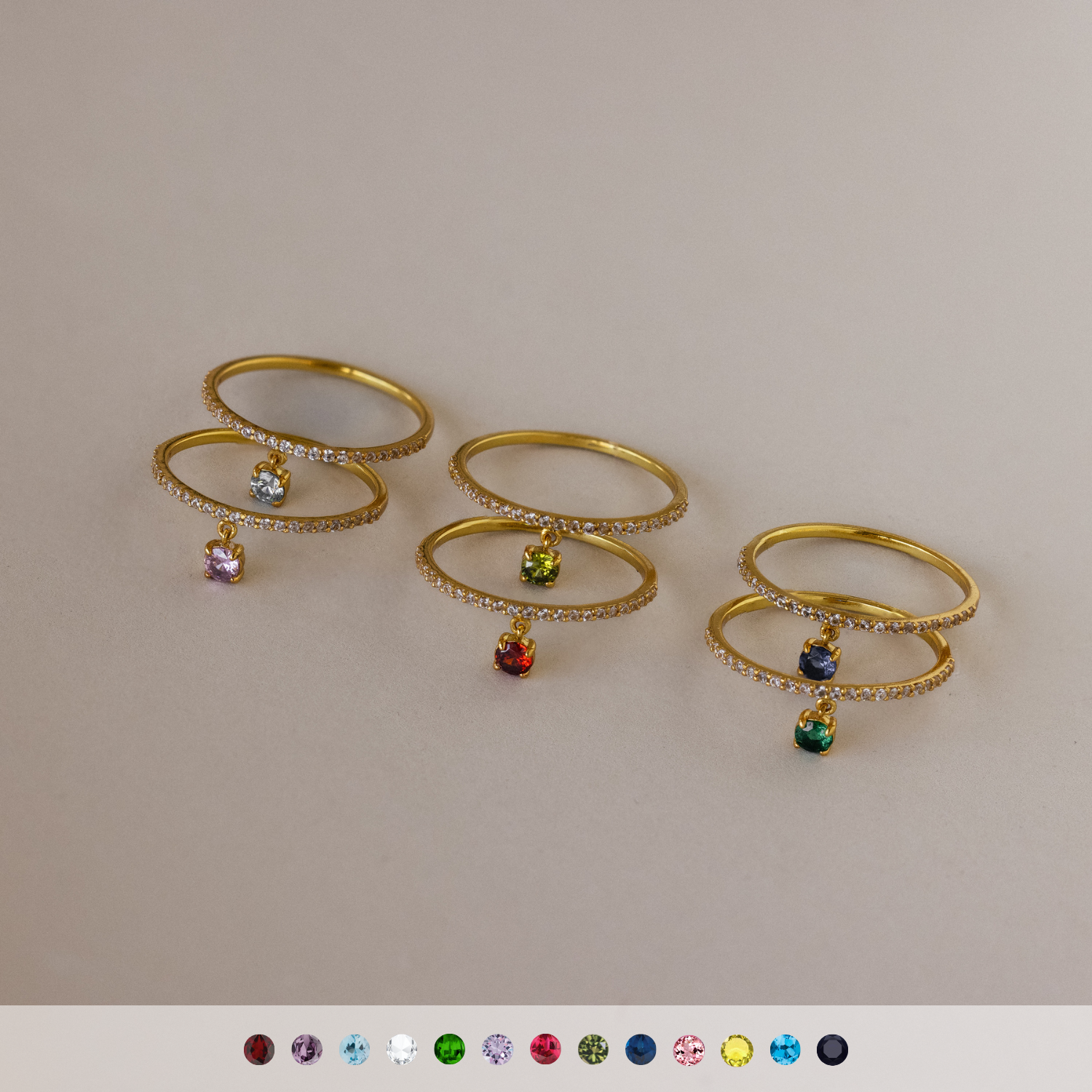 Four Pave Birthstone Drop Rings with colorful gemstones are displayed in a row, ideal for stacking as birthstone rings or mixing and matching to create personalized jewelry sets.