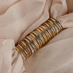 A striking full set of birthstone rings in gold finish, showcasing stones in every month’s color from garnet to zircon, wrapped over soft champagne-colored fabric.