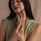 Model wearing a gold bubble letter ring with the name "ROMY" styled with multiple matching gold stacking and statement rings.
