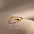 Up close of a dainty gold bubble letter gemstone duo ring with the initial "A" and a clear diamond birthstone.