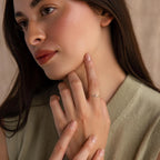 Model wearing a dainty silver bubble letter gemstone ring with the initial "S" and a green peridot birthstone.