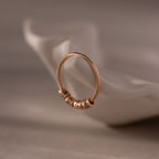 A Beaded Multiple Name Ring with engraved name charms rests on a white, curved ceramic dish.