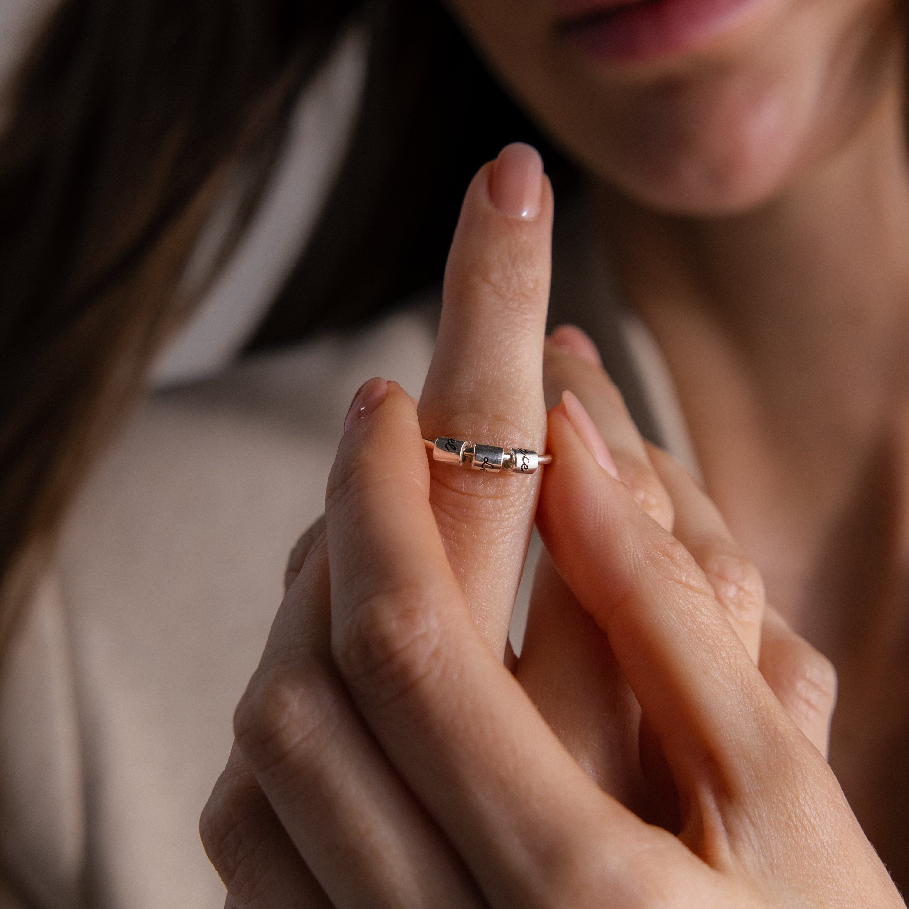 A woman with neatly manicured nails slips on a Beaded Multiple Name Ring, customized just for her.