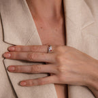A hand with neatly manicured nails wears the Toi et Moi Baguette Name Ring in Sterling Silver, resting on a beige blazer.