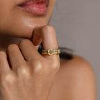 Close-up of a woman's hand near her face, wearing the gold Duo Birthstone Tennis Linked Ring Set with gemstone accents on her finger.