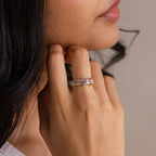 A woman's hand with the Duo Birthstone Tennis Linked Ring Set, featuring silver rings in a delicate minimalist design, rests gently on her face near her lips.