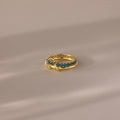 The Duo Birthstone Tennis Linked Ring Set in Blue Zircon (December) features blue gemstones set in a row on gold, displayed on a neutral, softly lit surface.