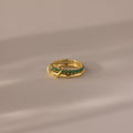 The Duo Birthstone Tennis Linked Ring Set in emerald (May) is displayed on a beige, softly lit surface.