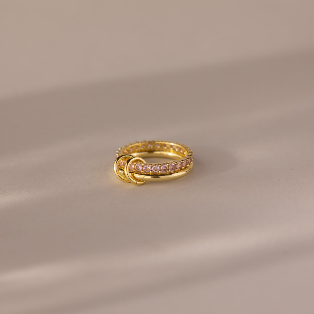 Duo Birthstone Tennis Linked Ring Set in Pink Tourmaline (October), featuring gold links and three small gold loops, displayed on a soft beige surface.