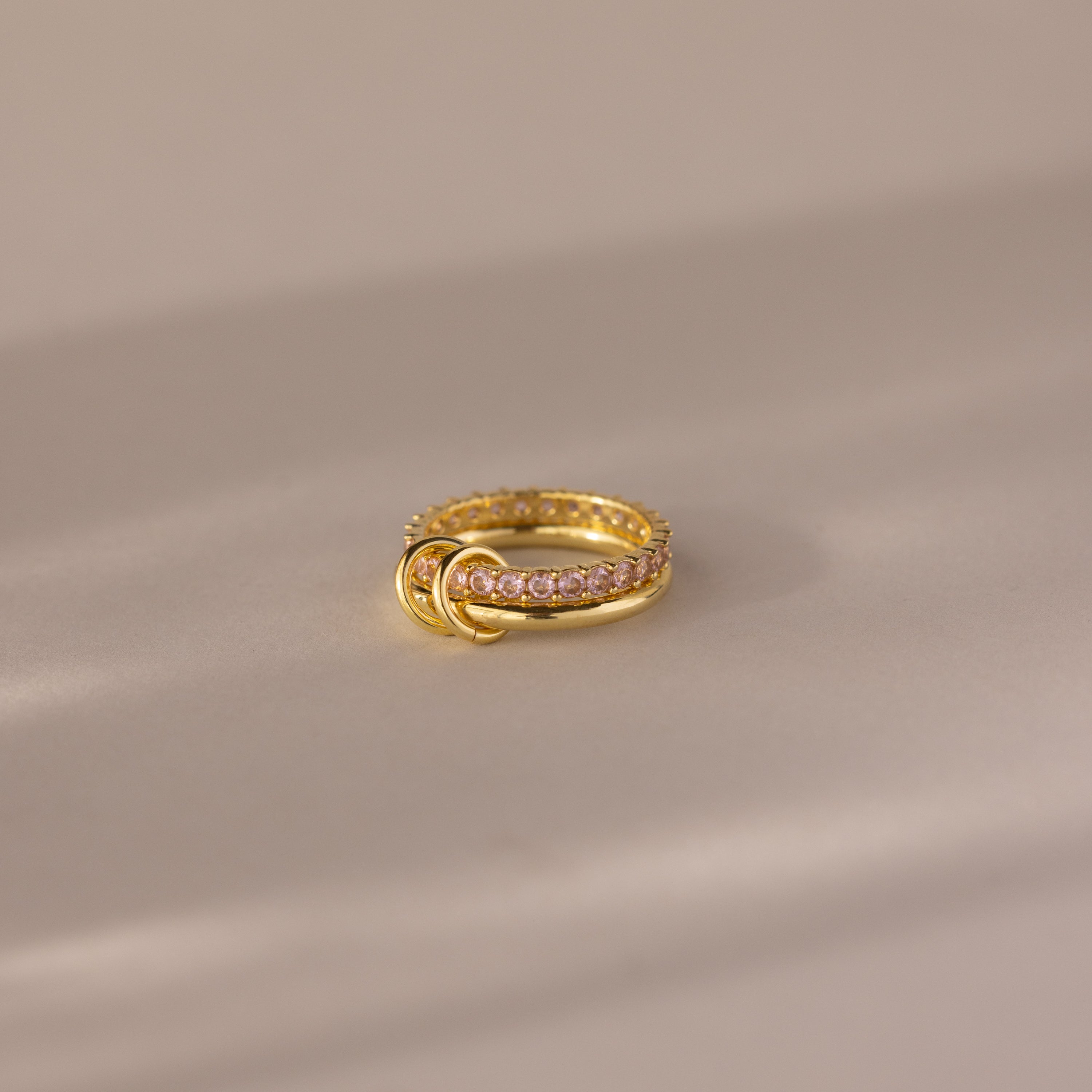 Duo Birthstone Tennis Linked Ring Set in Pink Tourmaline (October), featuring gold links and three small gold loops, displayed on a soft beige surface.